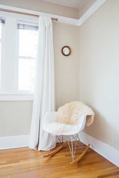 白色和棕色的摇椅靠近白色油漆墙和白色窗帘